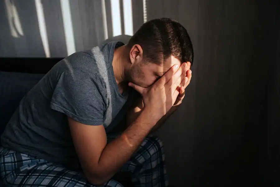 Man sitting alone with his hands covering his face
