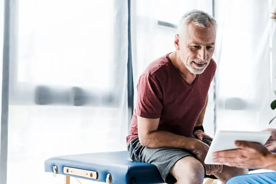 An older male patient reviewing health information with his clinician
